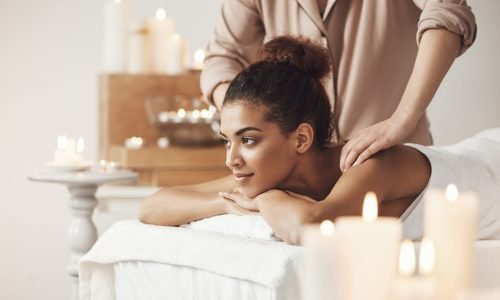 Young beautiful african girl smiling enjoying massage in spa resort.
